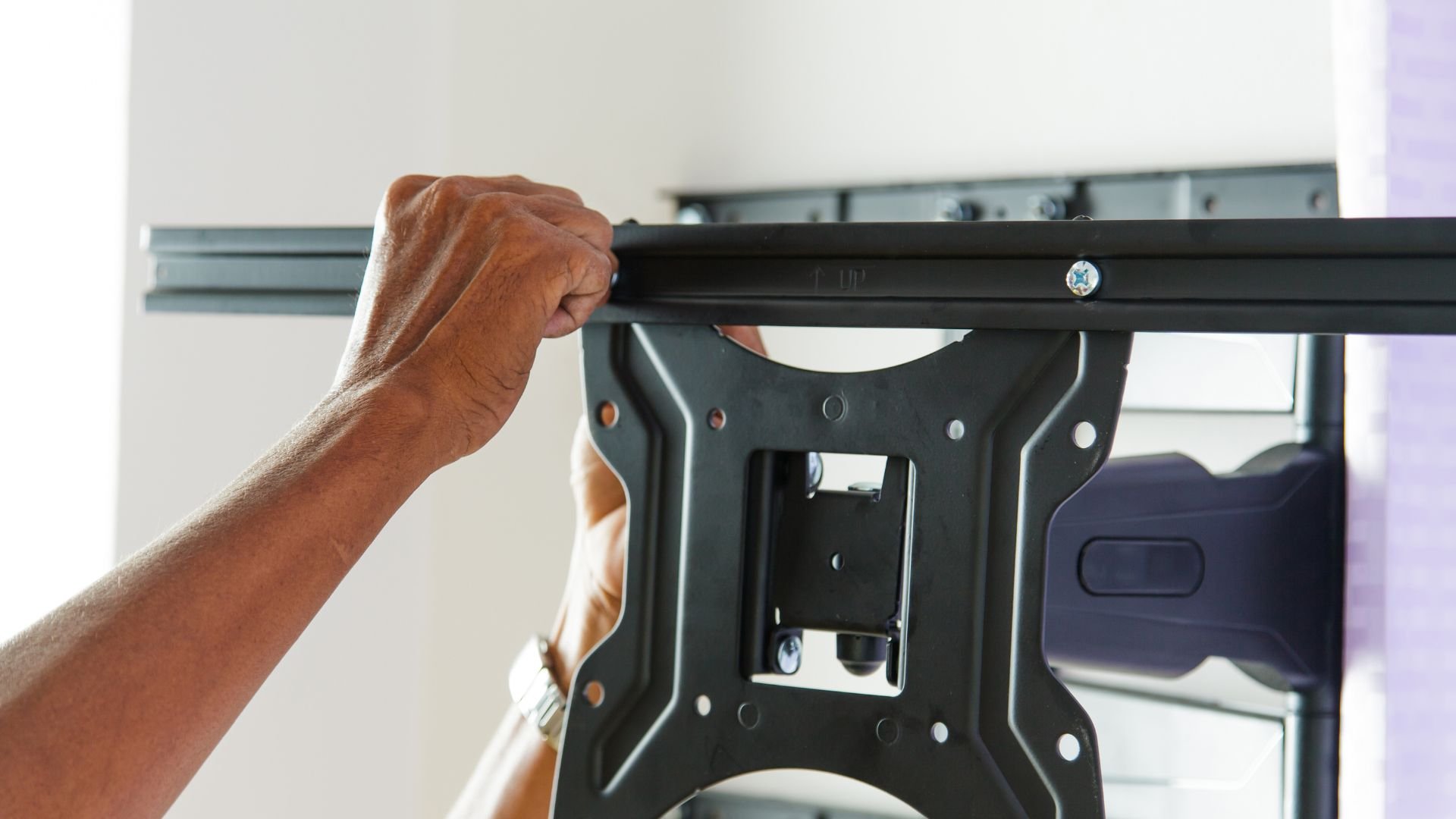 Hand installing TV wall mount bracket with metal mounting hardware