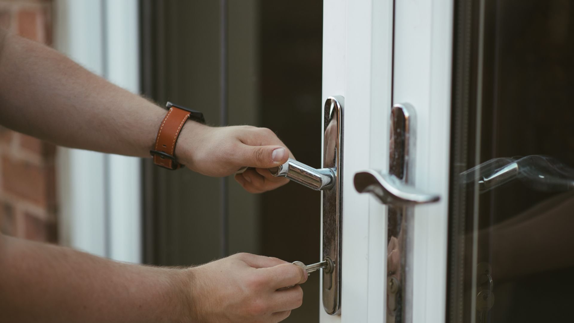 Hand turning key in modern white door lock with chrome handle